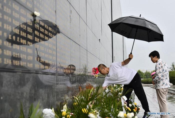 A resident presents flowers in front of a memorial wall at the Tangshan Earthquake Memorial Park in Tangshan, north China's Hebei Province, July 27, 2021. Wednesday marks the 45th anniversary of the Tangshan earthquake. The 7.8-magnitude quake struck the city of Tangshan in Hebei Province on July 28, 1976, killing more than 240,000 people and destroying virtually all buildings. (Xinhua/Mu Yu)