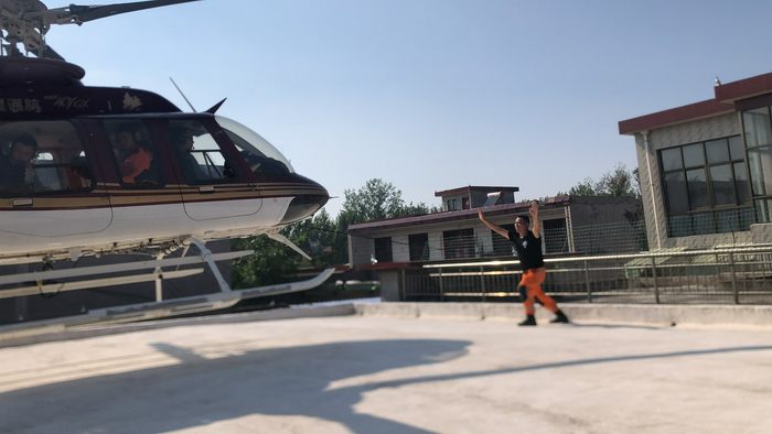 王建林以身体做标识，引导小型直升机降落到一个小的平台上