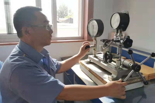计量检定员正在进行铁路双针压力表的校验（太原车辆段供图）