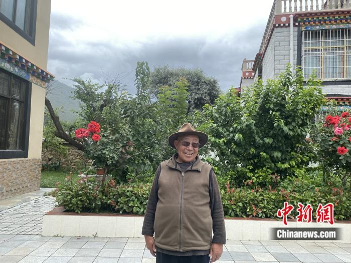 达龙老人在自家小楼前。彭宁铃 摄
