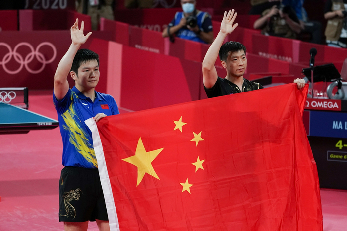 樊振东和马龙手举国旗。