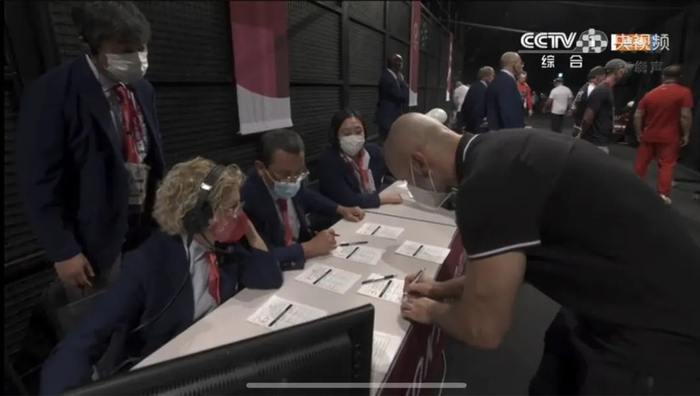 北京时间7月31日，举重男子81公斤级决赛，一位教练员在加重台修改试举重量（视频截图）