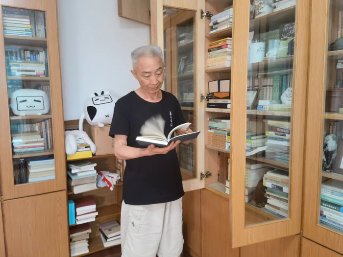 ▲7月5日，新京报记者采访戴建业，谈到兴致处，戴建业从书架上抽出书向记者分享。新京报记者 李照 摄