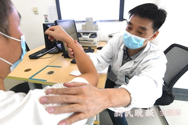 图说：杨星光正在为一名打羽毛球健身过程中扭伤肩关节的患者进行诊断  新民晚报记者 徐程 摄（下同）