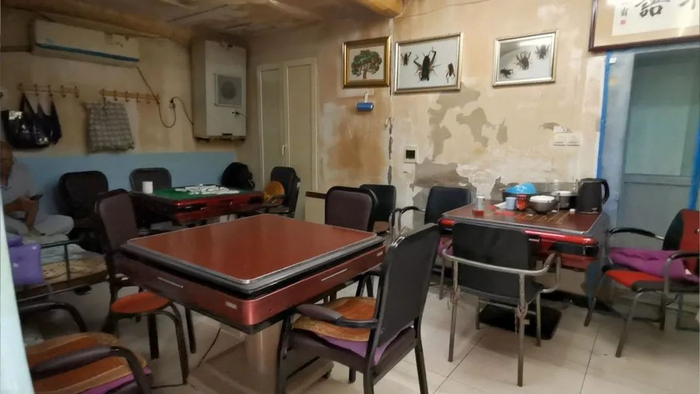 ▲这间棋牌室空间狭小，却挤下了三张牌桌还有一张单人床。8月7日晚上店家盘坐在床上休息。新京报记者 裴剑飞&nbsp;摄