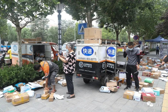 8月12日10时许，快递员将快递摆在小区大门外，等待居民来取件。