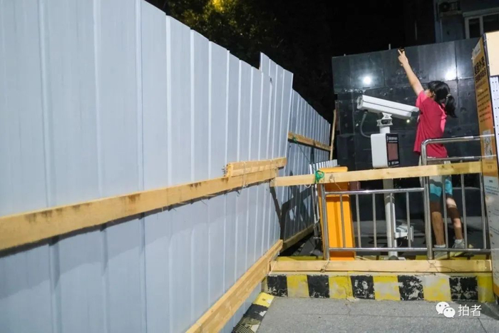 8月11日23时许，良庄家园，居民隔着围挡拍摄大门外风景。