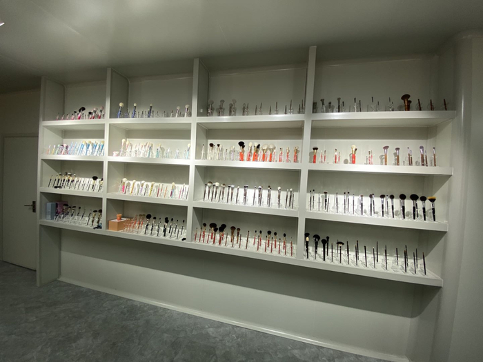 图说：康绍兴的办公室里有一整面墙的展示柜，上面放满了各式各样的化妆刷。摄影：吴琼