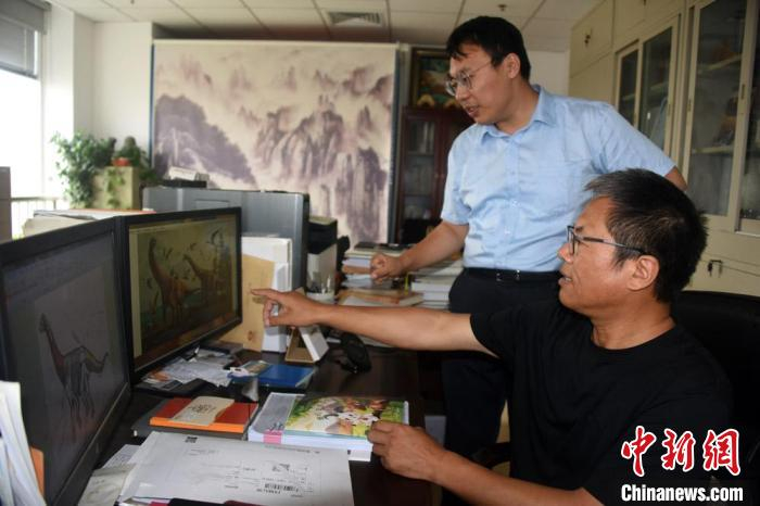 汪筱林研究员在办公室与论文作者之一、北京自然博物馆裘锐博士（站立者）进行讨论。　中新社记者 孙自法 摄