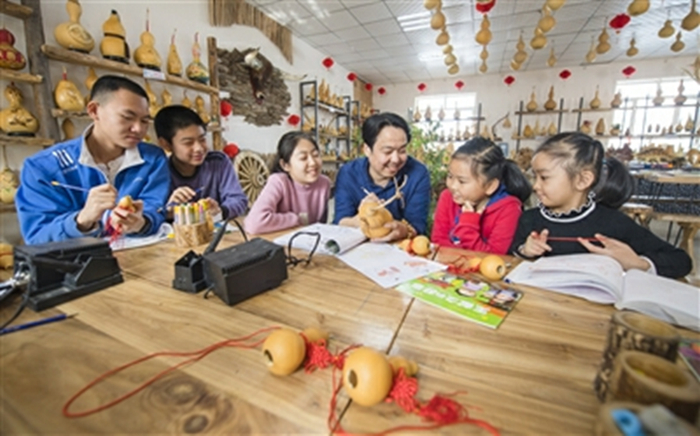 呼图壁县五工台镇幸福村乡村葫芦园，孩子们在学习葫芦雕刻。何龙摄央广网发