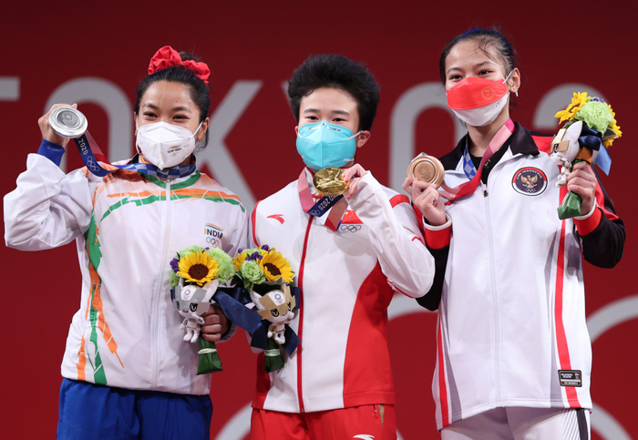 当地时间7月24日，中国选手侯志慧（中）获东京奥运会女子举重49公斤级项目金牌、印度选手米拉拜（左）和印尼选手艾萨分获银牌和铜牌。图自新华社