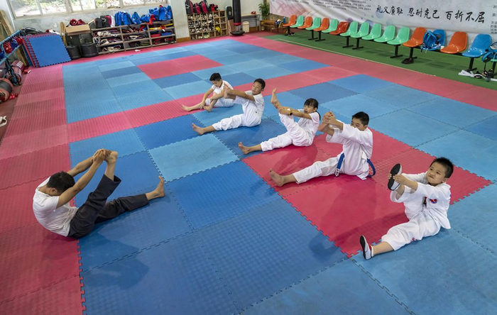  昆明市体育馆内，空手道培训班教练在带领学员做拉伸。