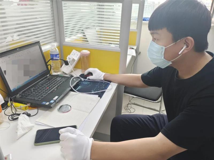 技术队勘查员在现场查看涉嫌诈骗人员使用的电脑。丰台警方供图