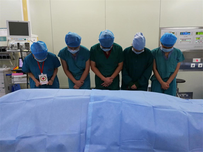 器官移植工作人员在省红十字会工作人员的引领下，对捐献者进行默哀和告别。