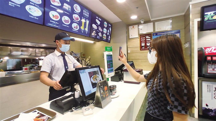  使用手机微信支付成为许多人的日常。图为西安市东关正街魏家凉皮店内消费者正使用微信支付结账。 本报记者 周恒宇摄