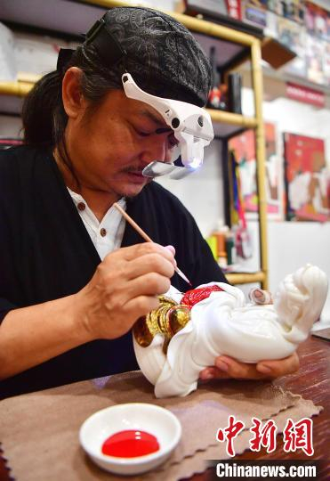 图为黄守堃正在对瓷烧观音像上第18道大漆。　张斌 摄