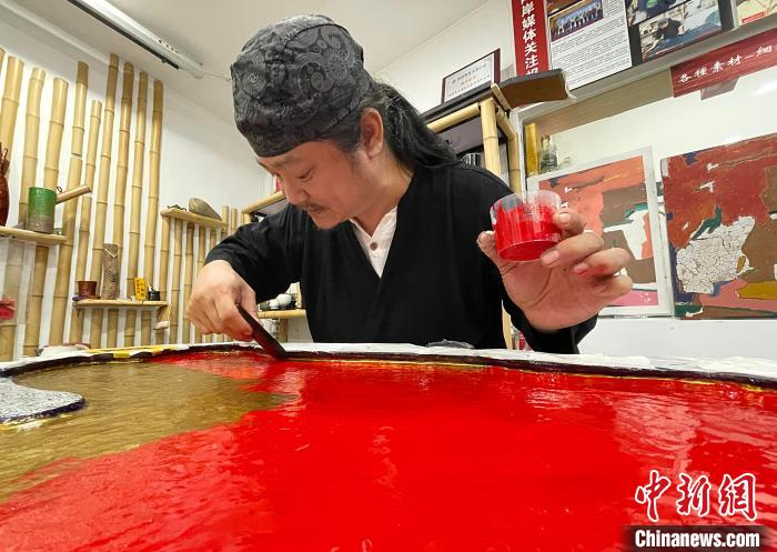 图为黄守堃正在制作定制的茶盘，他还采用了文物修复中展现立体图腾的技法将客户的姓氏图纹体现在茶盘上。　张斌 摄