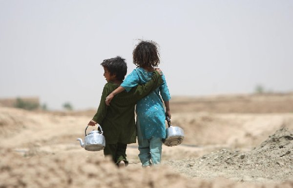 　　↑2013年6月12日，小姐弟两人手提茶壶在路上行走。新华社发（马苏德摄）