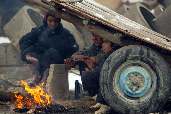 　　↑2009年1月13日，小贩在喀布尔雪地上烤火。新华社发（扎比摄）