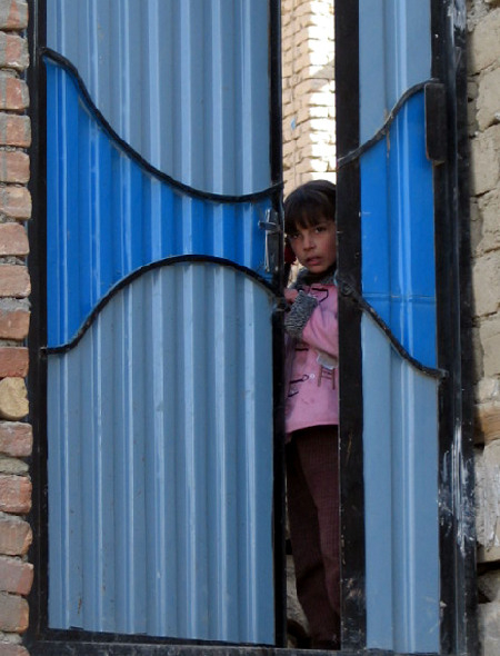 　　↑2006年1月23日，在喀布尔的一个难民营，一名儿童透过门缝向外张望。新华社发（扎比摄）