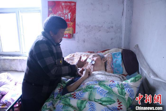 刘俊兰用注射器给丈夫喂水。　颜赛 摄