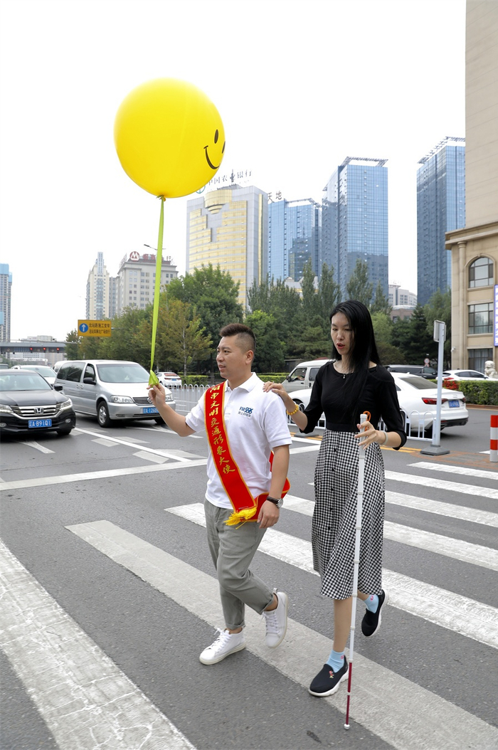 视力障碍人士在志愿者协助下过马路（央广网发 王雪摄）