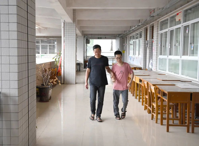 郑宇宸和父亲行走在河池高中教学楼的走廊里（8月18日摄）。新华每日电讯记者周华摄