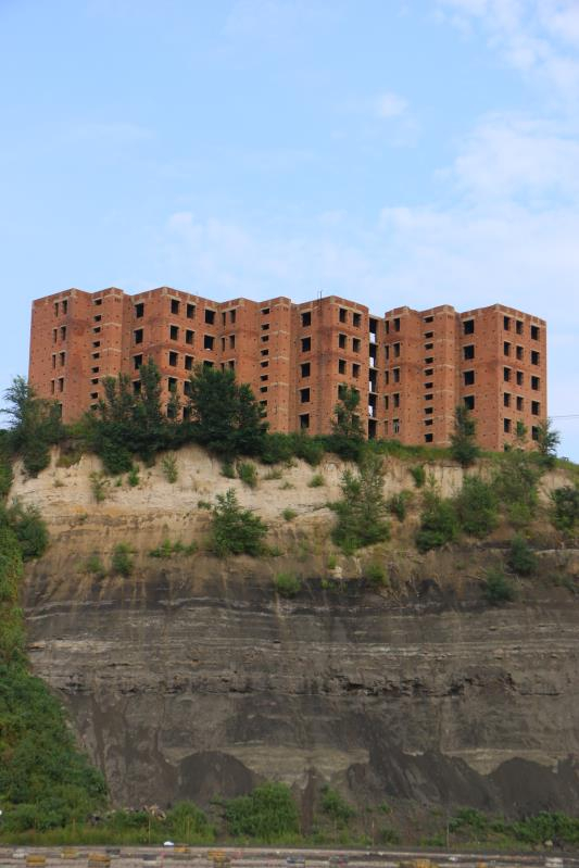 9月5日，举办草莓音乐节的废弃矿坑，黑色的煤层在山体上留下痕迹，上方有一处烂尾楼。新京报记者杜寒三摄