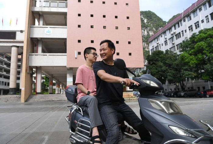 郑宇宸和父亲骑行在河池高中校园内，这样的路，父子俩一走就是三年。（8月18日摄）。新华每日电讯记者周华摄
