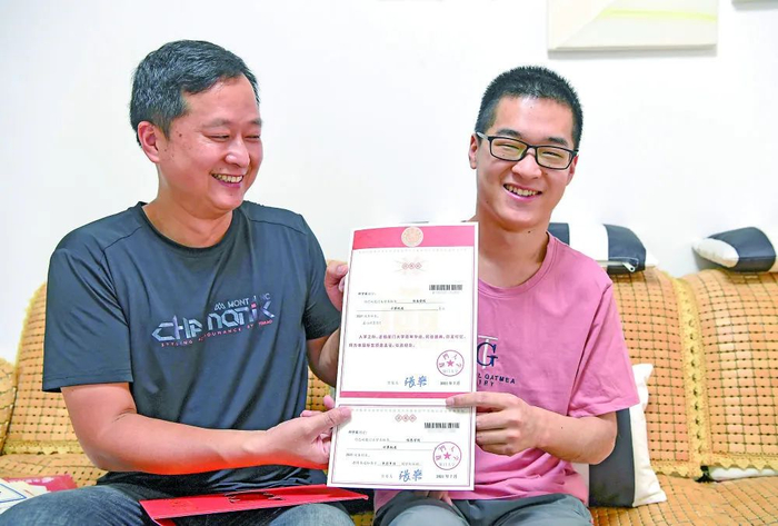 郑宇宸（右）和父亲在家里展示厦门大学的录取通知书（8月18日摄）。新华每日电讯记者周华摄