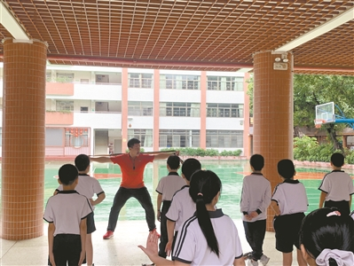 下雨天，体育老师带领学生在教学楼里上课。