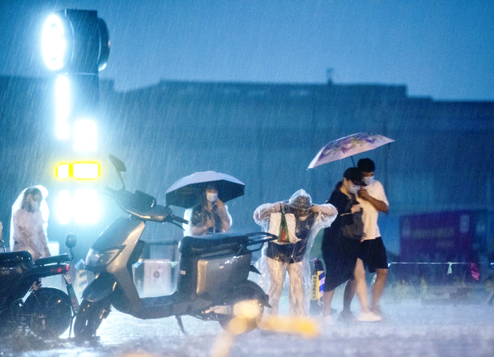 2021年8月9日，北京一地铁站口，市民冒雨前行。新京报记者 陶冉 摄