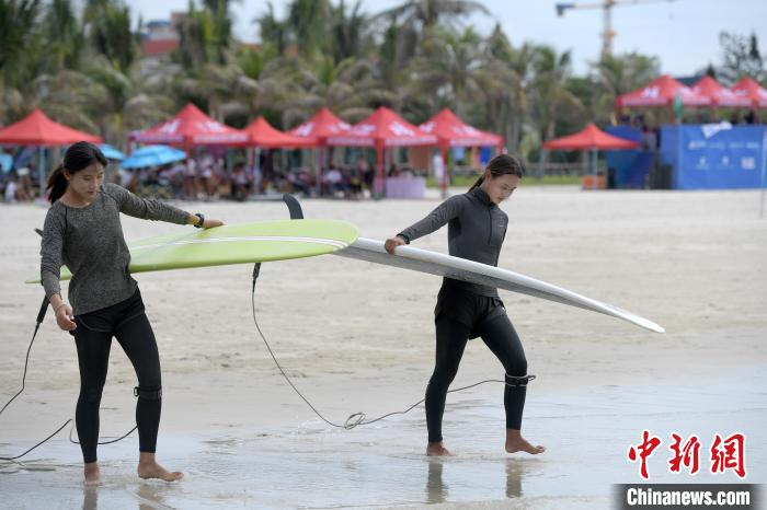 图为参赛者手持冲浪板前往海边热身。　俞靖 摄