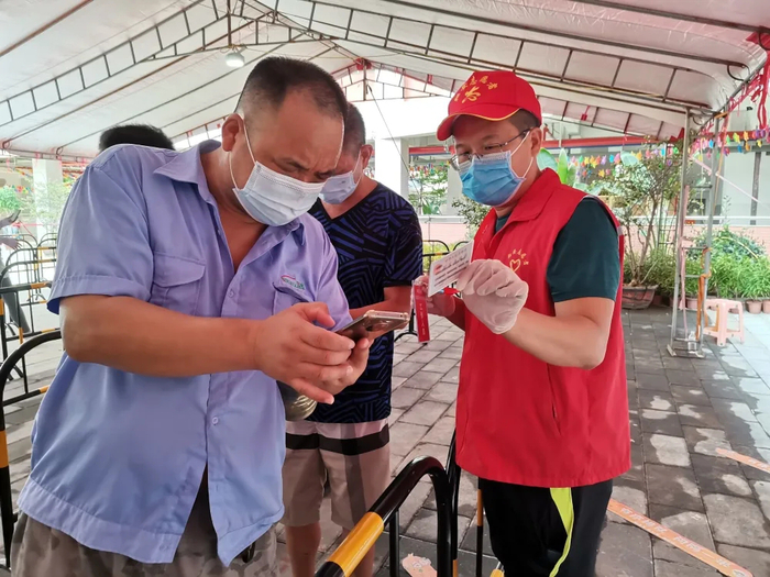 检察志愿者们在检测采样点现场帮助居民注册检测码。