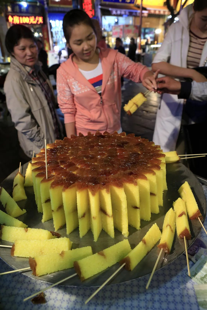 游客在西安回坊小吃一条街购买风味小吃桂花糕。新华社记者 李明放 摄