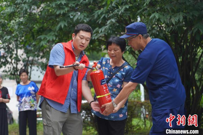 衢州龙游县龙洲街道城建办联合公安、消防、市监部门工作人员在社区开展消防知识宣传，教授居民使用灭火器。　叶肖翠 摄