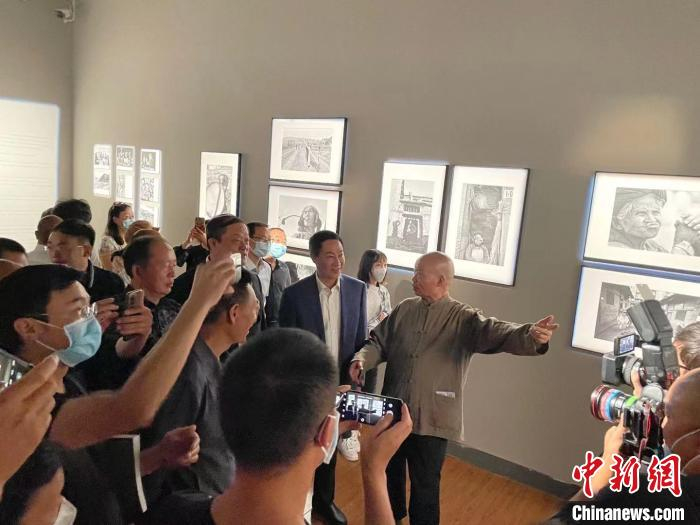 图为吴家林在为参观者介绍自己的摄影作品。　缪超 摄