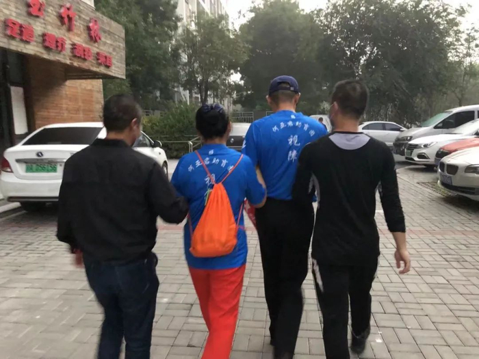 ▲卜有枫带着三个同事走在路上，四人呈横队一条线，卜有枫在最前方引路。新京报记者 冯雨昕 摄