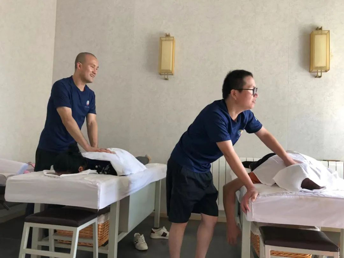 ▲何亚君（左）在店里给客人按摩。新京报记者 冯雨昕 摄
