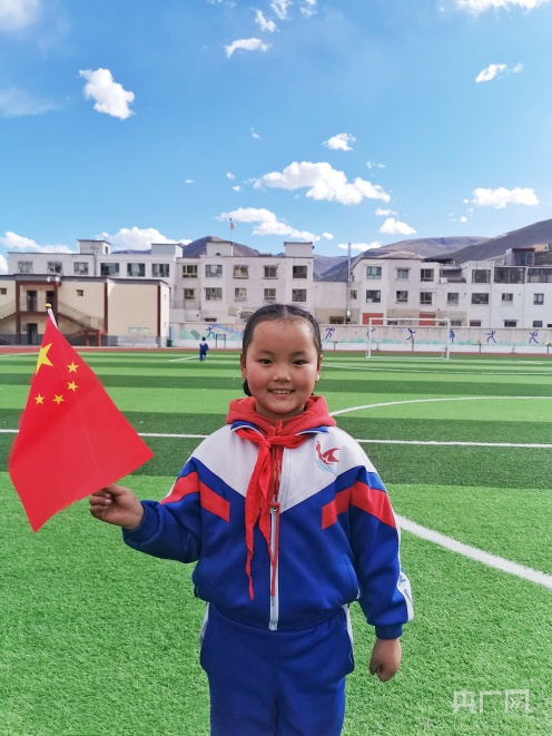 玉树藏族自治州红旗小学学生与国旗合影（央广网发 卓尕文毛 摄）