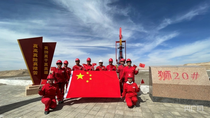 国庆节前夕，青海油田采油三厂狮子沟采油作业区采油二班当班职工在世界海拔最高的采油作业区狮20井前与国旗合影。（央广网发 杜雪峰摄）