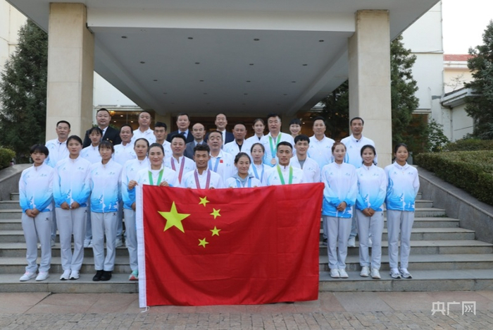 参加第十四届全运会青海代表团的部分成员与国旗合影（央广网发 杨长伟 摄）