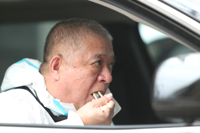 刘国贤穿着防护服在车内吃饭。