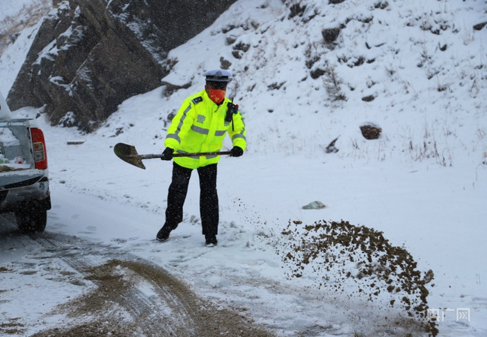 民警王文在路上拋洒防滑沙。央广网发