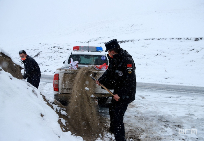 喀纳斯景区公安局民警帕尔夏提在往警车上装防滑沙。央广网发