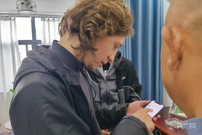 Artem询问并体验民宿预定（央广网发 王锡斐摄）