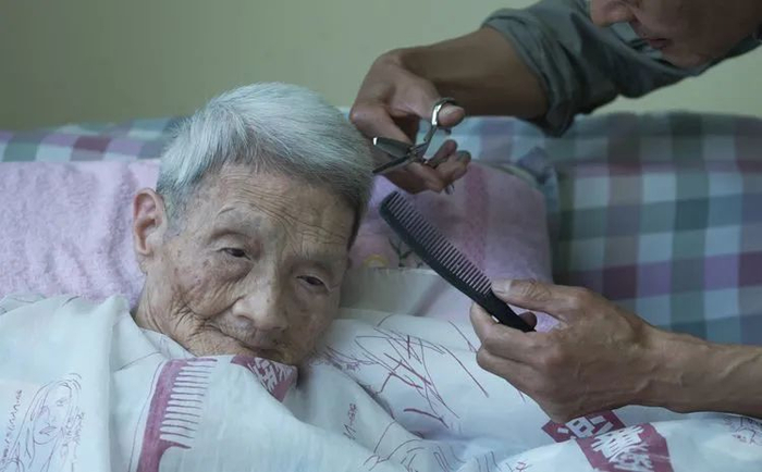 ▲一位老人的儿子在医院为母亲剪发，医养中心尤其重视让家人定期探访，和老人相处，抚慰老人。