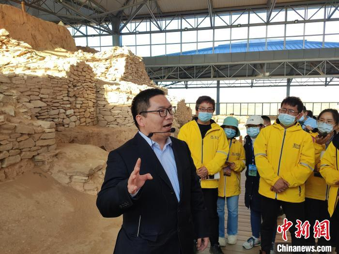 西北大学丝路研究院副院长席会东教授向采访团一行介绍石峁遗址。　中新网记者 陈海峰 摄