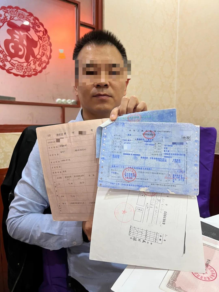 10月14日，郑晓方出示自己手中的房产证和缴税凭据。新京报记者杨雪摄