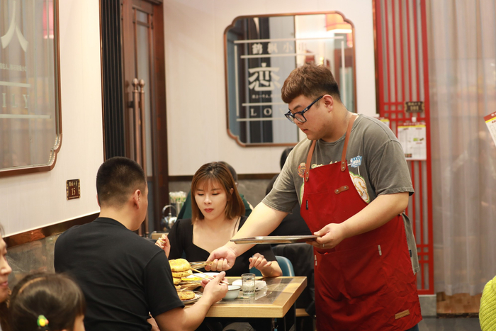 张学枫给客人上菜。